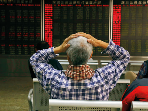 An investor reacts near boards displaying stock market prices in Beijing, China, Thursday, Dec. 6, 2018. 