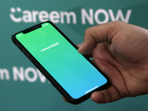 Careem CEO, Mudassir Sheikha shows the logo of the company's delivery service Careen NOW on his mobile at the company headquarters in Dubai.