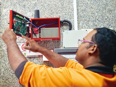 A technician installs a smart fire alarm system in a residential building. Photo for illustrative purpose only