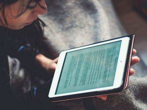 A woman reading a book on her iPad.