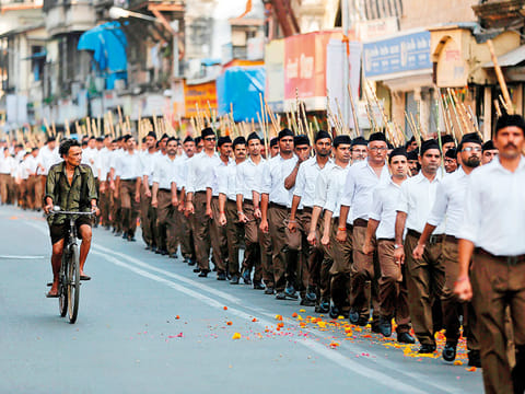 A man rides his bicycle past volunteers of the Hindu nationalist organisation Rashtriya Swayamsevak Sangh (RSS) taking part in Route March in Mumbai (File image)