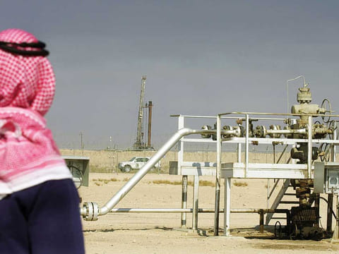 An oil well in the Ratqa oilfield, in the northern Kuwaiti desert, just a few hundred metres from the Iraqi border where an oil rig of the Iraqi Oil Company can be seen.