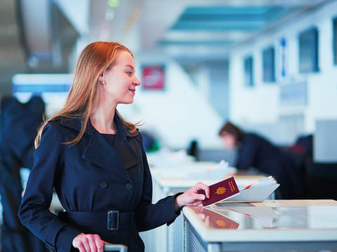 A traveller presents her passport at an airport check-in counter. 