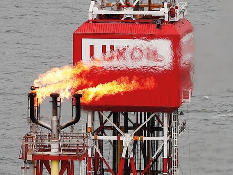 A gas torch is seen next to the Lukoil company sign at the Filanovskogo oil platform in the Caspian Sea, Russia. 