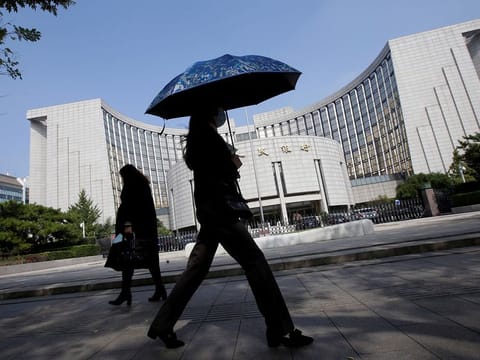 People walk past the headquarters of the People's Bank of China (PBOC), the central bank, in Beijing, China.
