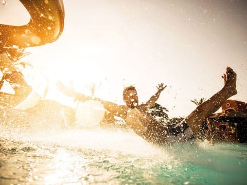 Man having fun in water park while sliding into the water
