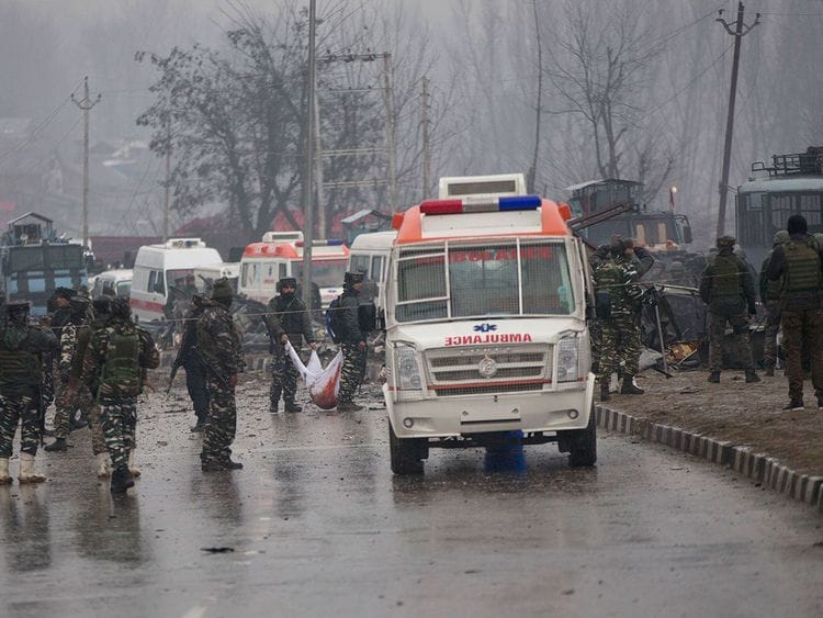 Indian paramilitary soldiers carry the remains