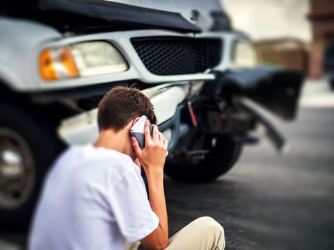 A teenager on the phone after a car accident.