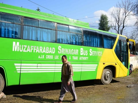 A Pakistani Kashmiri walks past a bus doing the Muzaffarabad-Srinagar Bus Service parked on a street, in Muzaffarabad, the capital of Pakistan's controlled Kashmir following a shut down of the bus service connecting the cities. 
