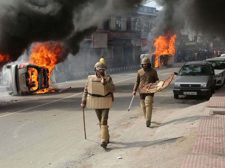 Policeman walk past vehicles set on fire