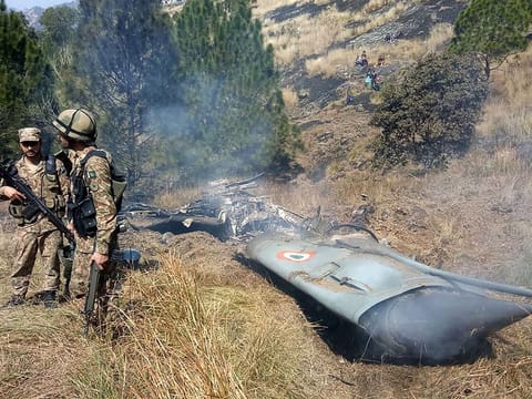 Pakistani soldiers stand next to what Pakistan says is the wreckage of an Indian fighter jet shot down in Pakistan controled Kashmir at Somani area in Bhimbar district near the Line of Control on February 27, 2019.  