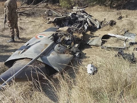 A Pakistani soldier stands guard near the wreckage of an Indian plane shot down by the Pakistan military on Wednesday, in Hurran, near the Line of Control in Pakistani Kashmir, on Thursday, February 28, 2019. 