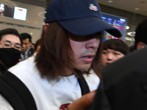 This picture taken on March 12, 2019 shows K-pop star Jung Joon-young (C) surrounded by reporters as he arrives at Incheon international airport in Incheon. A burgeoning K-pop sex scandal claimed a second scalp as a singer who rose to fame after coming second in one of South Korea's top talent shows admitted secretly filming himself having sex and sharing the footage. 