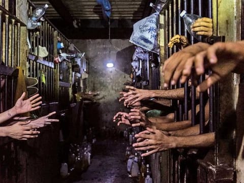 Prisoners beg for food and water at their cells in a police station. Many said they had regular jobs but turned to crime because of the impossibility of bringing food home.