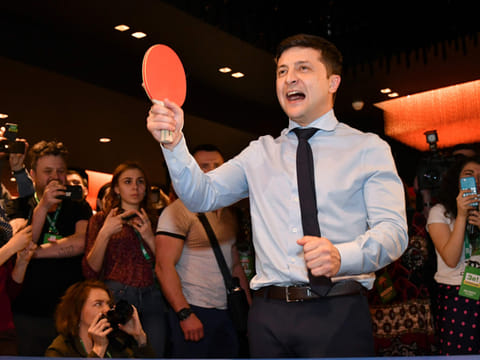 Ukrainian comic actor, showman and presidential frontrunner Volodymyr Zelensky surrounded by cameramen and photographers plays table tennis with a journalist ahead of the provisional results at the headquarter in Kiev on March 31, 2019.