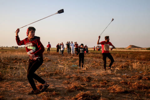 A Palestinian uses a slingshot during a demonstration near the border with Israel, east of Khan Yunis in the southern Gaza Strip, on April 12, 2019. 