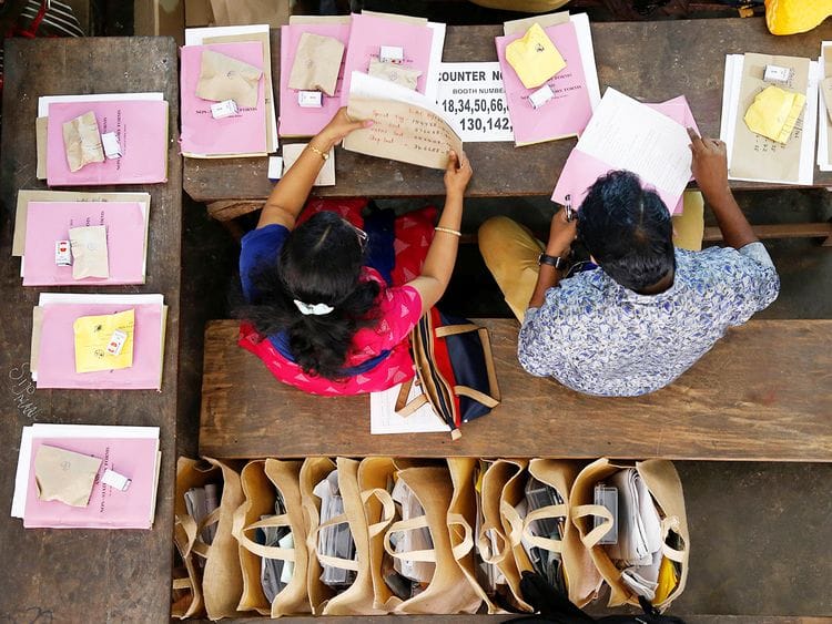 Election officials sit next to election materials