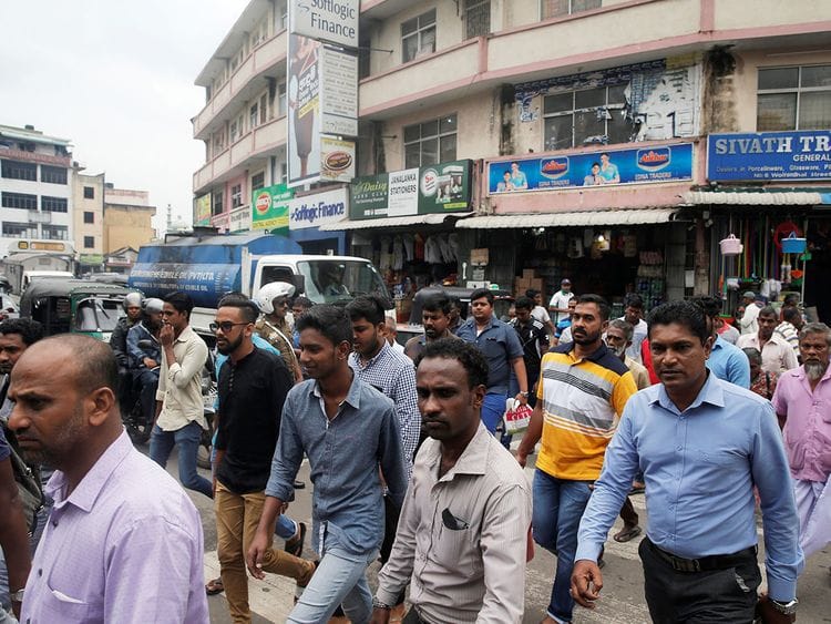 People cross a street in central Colombo