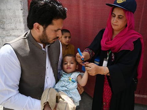 A polio vaccination worker marks the finger of a child after administering with anti-polio drops during a door-to-door polio immunisation campaign on the outskirts of Islamabad. 