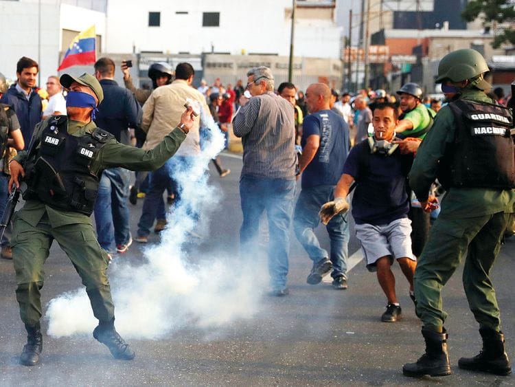 A military member throws a tear gas canister