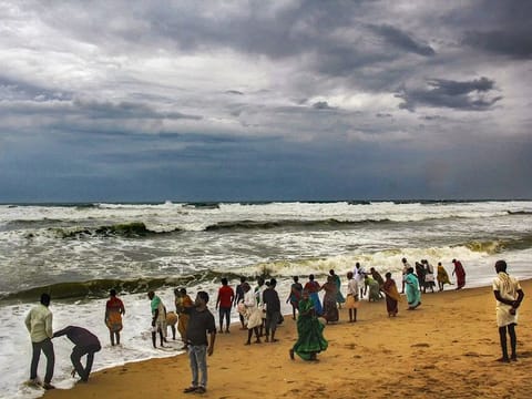 Villagers at the beach as dark clouds hover above the sea ahead of cyclone 'Fani', in Puri, Thursday, May 2, 2019. 