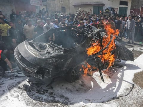 Palestinian emergency personnel try to put out the fire on a car belonging to Hamas member Hamad Al Khodori, in Gaza City on May 5, 2019, after it was hit by an Israeli airstrike.