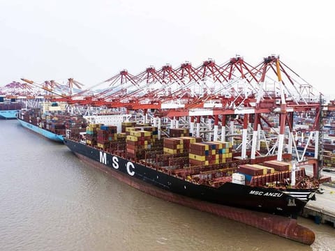 The Mediterranean Shipping Co. (MSC) Anzu container ship, front, is docked next to gantry cranes at the Yangshan Deepwater Port, operated by Shanghai International Port Group Co. (SIPG), in this aerial photograph taken in Shanghai, China, on Friday, May 10, 2019.