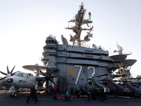Flight deck personnel stand on the flight deck on board the Nimitz-class aircraft carrier USS Abraham Lincoln (CVN 72) as it patrols the Arabian Gulf during a Strait of Hormuz transit 