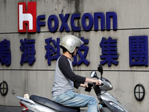 A motorcyclist rides past the logo of Foxconn, the trading name of Hon Hai Precision Industry, in Taipei, Taiwan.