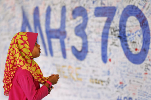 A girl looks at a board with messages of support and hope for passengers of the missing Malaysia Airlines MH370 at the Kuala Lumpur International Airport March 15, 2014.