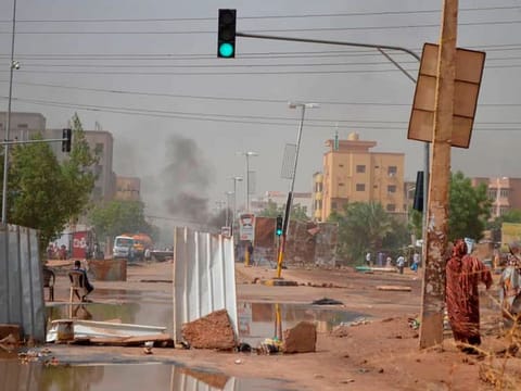 Smoke rises behind barricades laid by protesters to block a street in the Sudanese capital Khartoum to stop military vehicles from driving through the area on Wednesday