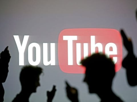 People pose with mobile devices in front of a screen projected with a YouTube logo