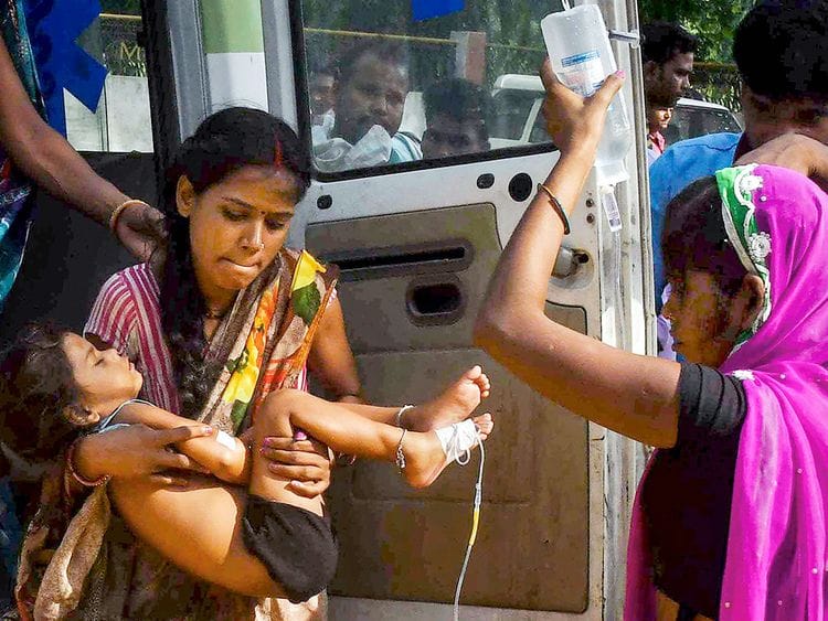 A woman carrying a child showing symptoms of Acute Encephalitis Syndrome