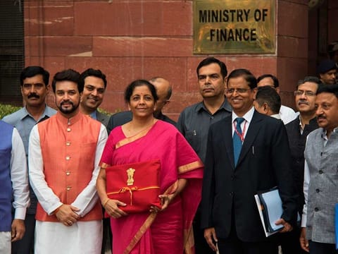 Indian Finance Minister Nirmala Sitharaman, center left, and junior Finance Minister Anurag Thakur, left, stands for the media outside the finance ministry before proceeding towards the parliament house to unveil the annual federal budget in New Delhi, India, Friday, July 5, 2019. 