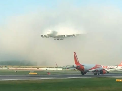 An Emirates A380 landing through a bed of low clouds. 