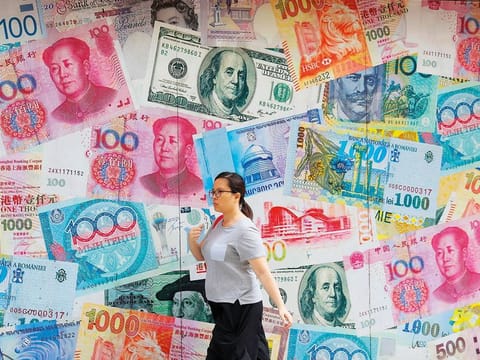 A woman walks by a money exchange in Hong Kong. China’s yuan fell further yesterday against the dollar, fueling fears about increasing global damage from Beijing’s trade war with Trump.