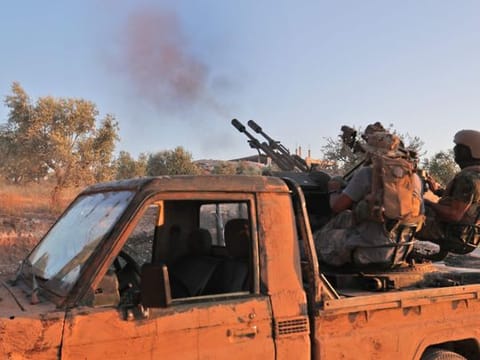 A fighter from the former Al Qaida affiliate Hayat Tahrir Al Sham fires an anti-aircraft gun in Syria's southern Idlib province on August 7, 2019.
