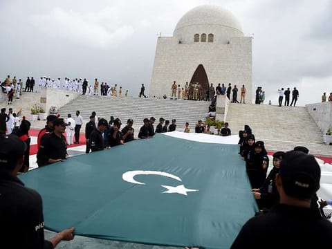 Pakistani police with the Special Security Unit (SSU) hold a national flag in front of the mausoleum of founding father Quaid-e-Azam Mohammad Ali Jinnah during Independence Day celebrations in Karachi