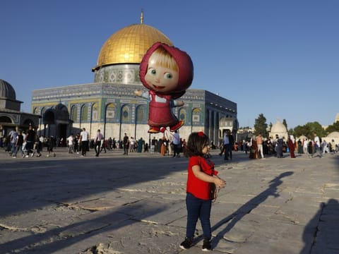 A Palestinian girl walks with her balloon in front of the Dome of the Rock mosque inside Jerusalem's Al-Aqsa mosque compound, Islam's third most holy site
