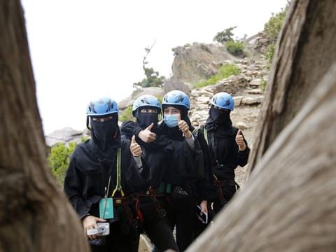 Saudi tourists wear helmets and keep their faces and hair covered according to local custom, as they pose for a photo before zip lining between cliffs, during the al-Soudah festival in Abha, southwest Saudi Arabia. 
