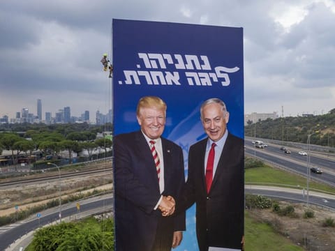 A worker hangs an election campaign billboard of the Likud party showing US President Donald Trump, left, and Israeli Prime Minister Benjamin Netanyahu in Tel Aviv. 