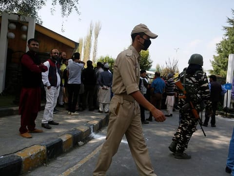 Indian policeman and a paramilitary soldier guard as relatives of Kashmiri political workers who have been detained wait to meet them outside a hotel turned into a detention center in Srinagar, Indian controlled Kashmir, Wednesday, Oct. 2, 2019.