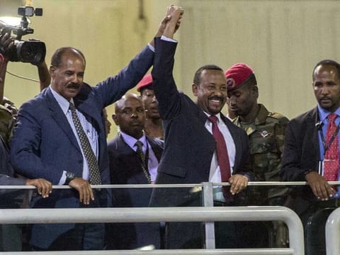 Eritrean President Isaias Afwerki (second left) and Ethiopia's Prime Minister Abiy Ahmed (middle) hold hands as they wave at the crowds in Addis Ababa on July 15, 2018. 