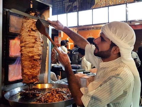 Abu Amir busy cutting the fresh slices of meat for shawarma for the people gathered around his food stand “Syrian Taste” in F-10 area of Islamabad