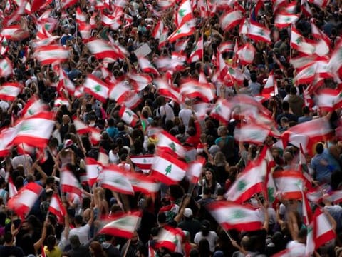 Demonstrators wave Lebanese national flags during ongoing anti-government protests at a highway in Jal el-Dib, Lebanon
