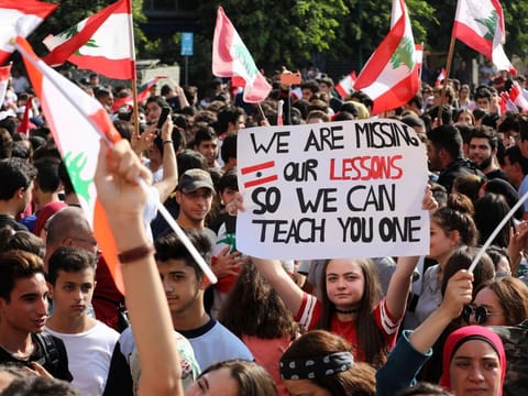 Lebanese students from various schools wave national flags and shout slogans as they gather in front of the Ministry of Education during ongoing anti-government protests, in the capital Beirut on November 7, 2019. 