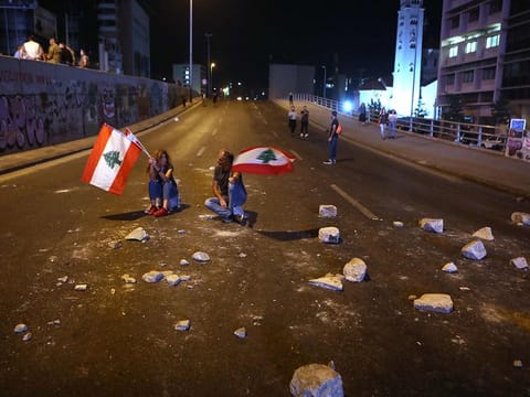 Lebanese anti-government protesters wave their country's flag as they block a main avenue in reaction to the speech of Lebanon's president Michel Aoun in Beirut on November 11, 2019. 