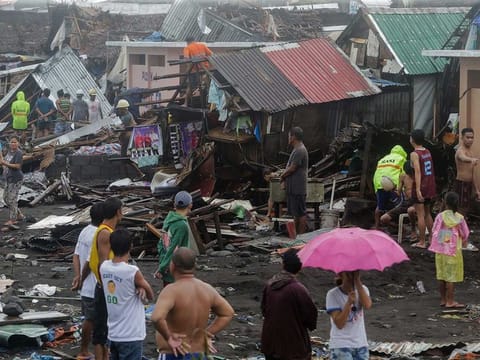 Residents stand among their damaged houses after Typhoon Kammuri hit Legazpi City, Albay, Philippines.