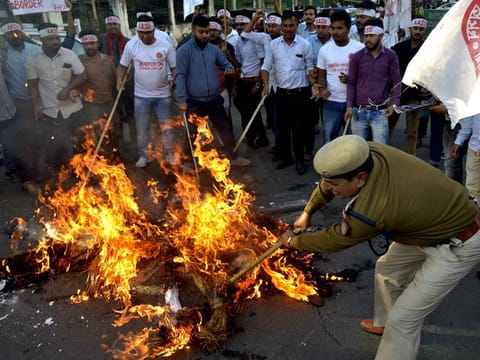 Police personnel trying to douse the effigies during a protest against the 'Citizenship Amendment Bill 2016' in Guwahati.