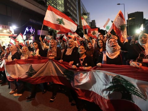 Residents of the Lebanese capital carry national flags as they take part in ongoing anti-government demonstrations in central Beirut on November 30, 2019.  More than a month into unprecedented anti-government protests, Lebanon is facing a dual political and economic crisis. / AFP / ANWAR AMRO